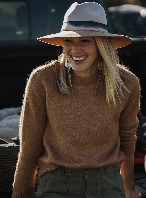 Brit Trible wearing white hat, brown sweater, and green pants. Brit Trible is founder of Gilded Lily Designs.