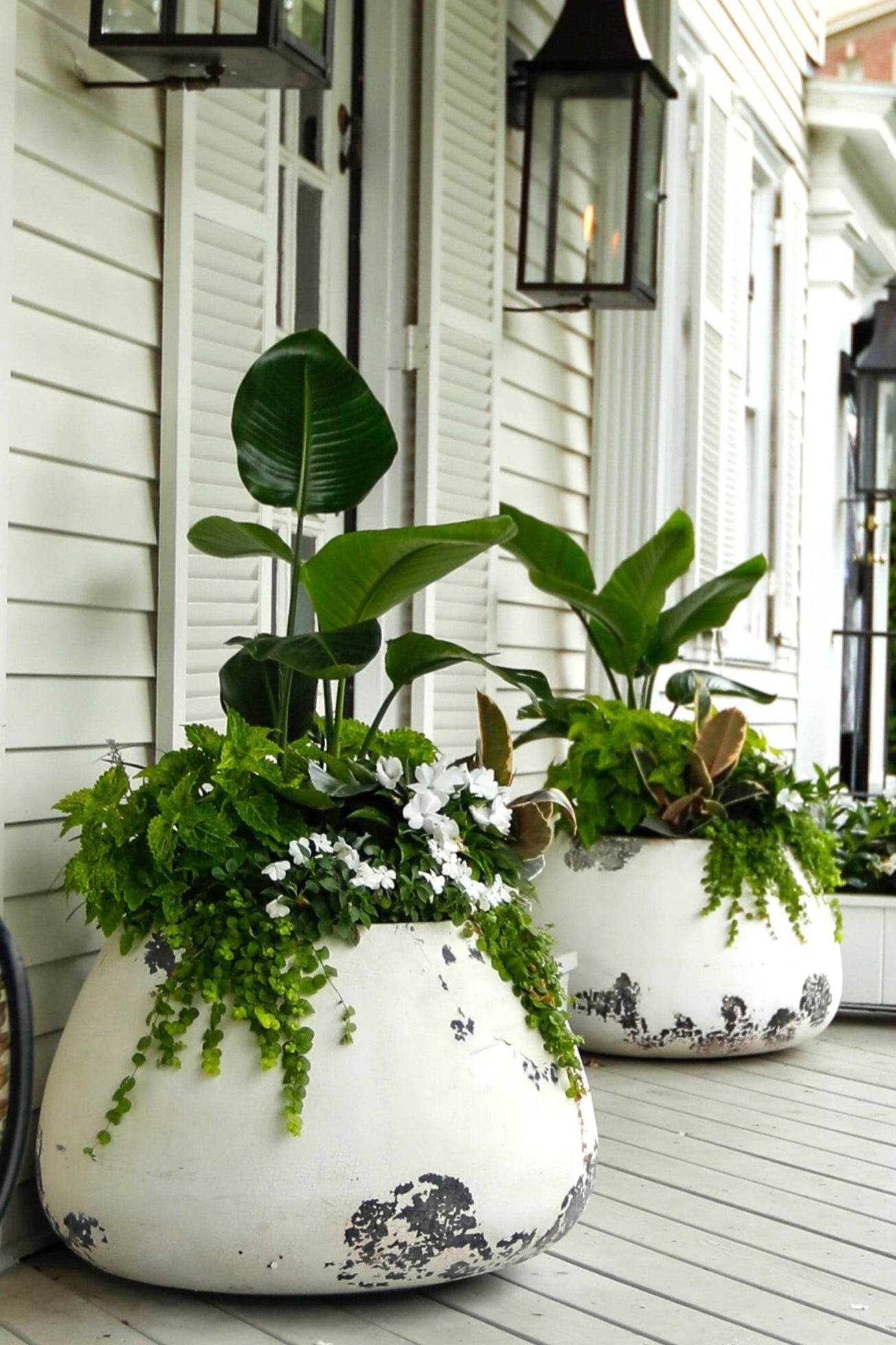 Decorative planters on a porch with a house in the background