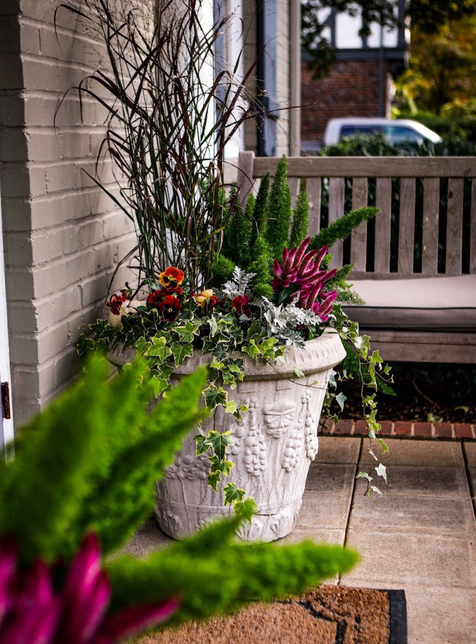 Fall pot filled with green plants and purple, yellow , and red flowers